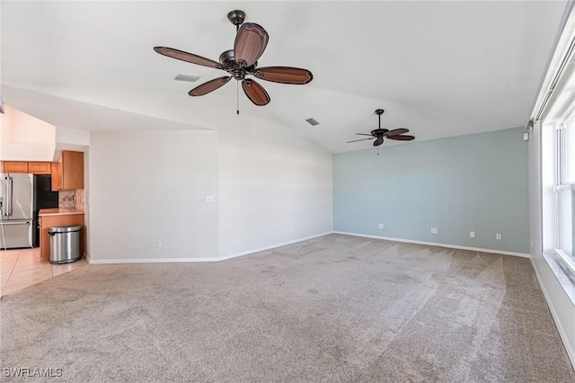 unfurnished living room with vaulted ceiling, light colored carpet, and ceiling fan