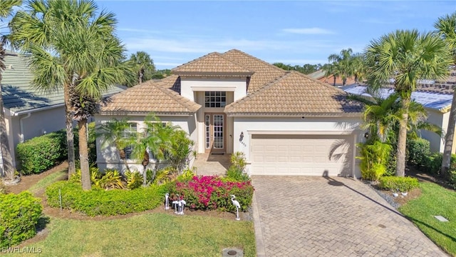 mediterranean / spanish home featuring a garage and a front lawn