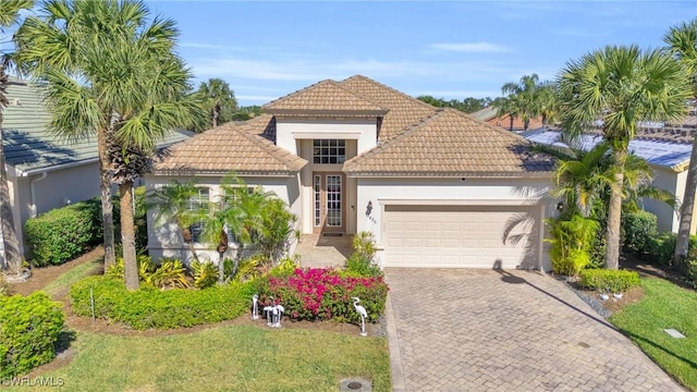 12890 Kentfield Ln, Fort Myers, FL 33913 - view of front facade with french doors, a tile roof, driveway, a garage, and stucco siding