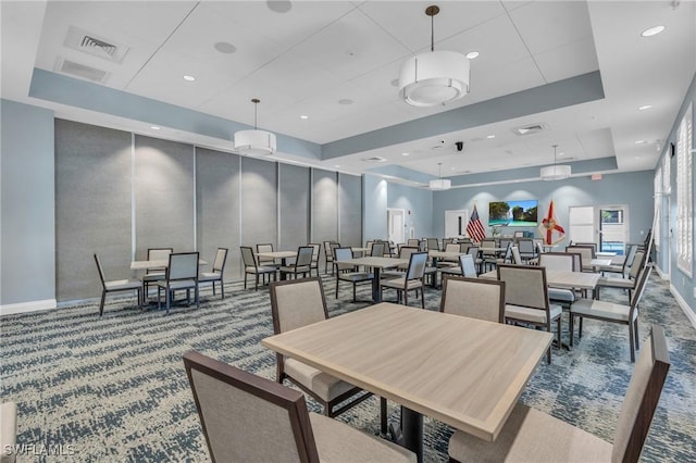 carpeted dining area featuring a raised ceiling