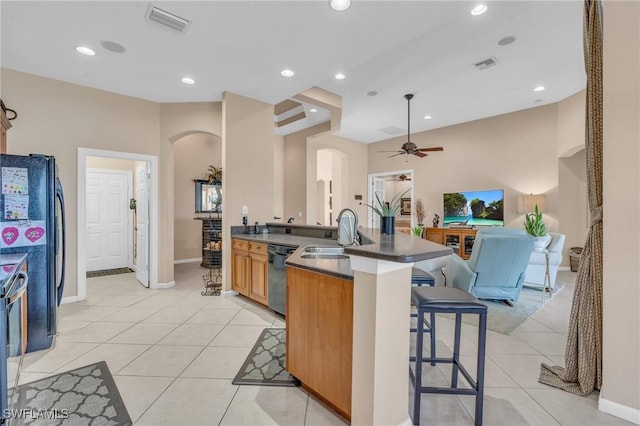 kitchen with black appliances, light tile patterned floors, a kitchen breakfast bar, and sink