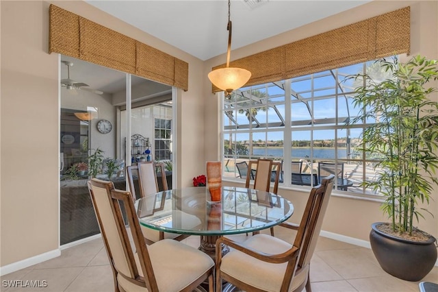 dining space with a water view, light tile patterned floors, and ceiling fan