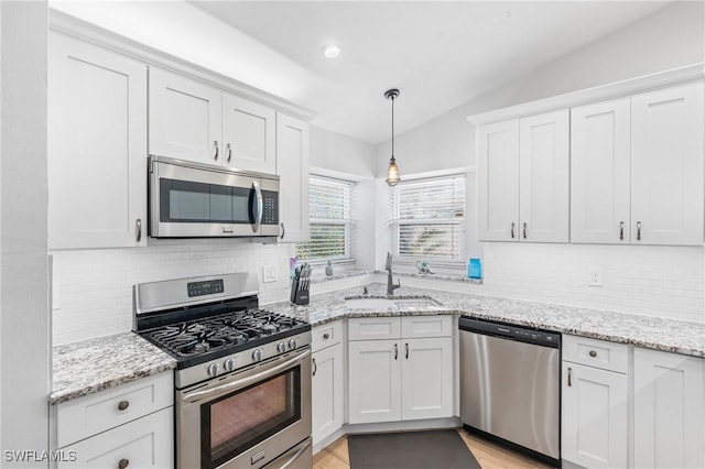 kitchen with decorative light fixtures, white cabinetry, lofted ceiling, sink, and stainless steel appliances