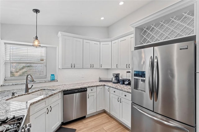 kitchen featuring pendant lighting, sink, appliances with stainless steel finishes, white cabinetry, and light hardwood / wood-style floors