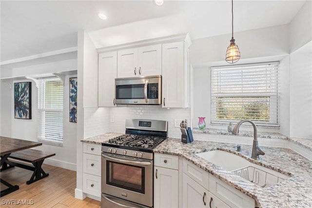 kitchen with sink, stainless steel appliances, white cabinets, and light stone countertops