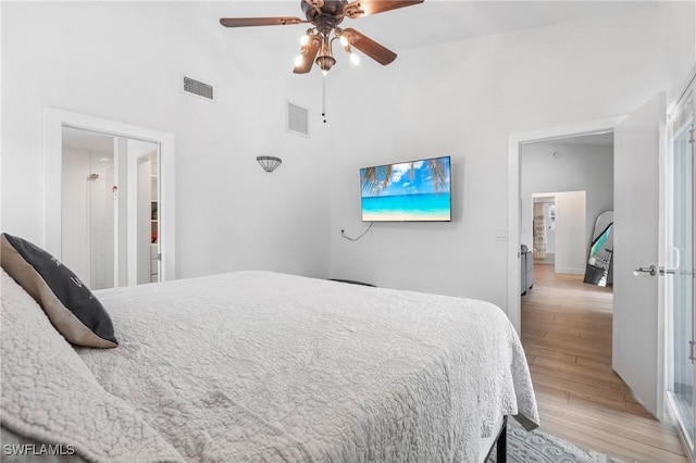 bedroom with ceiling fan, light hardwood / wood-style floors, and a towering ceiling