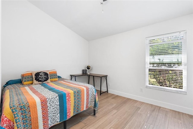 bedroom with lofted ceiling, multiple windows, and light hardwood / wood-style flooring