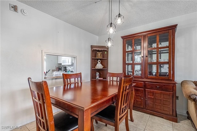 dining room with vaulted ceiling, a textured ceiling, and light tile patterned flooring