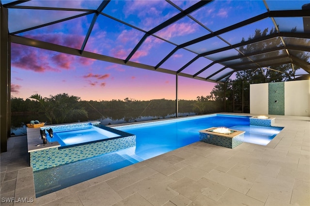 pool at dusk featuring a patio area, an in ground hot tub, pool water feature, and glass enclosure