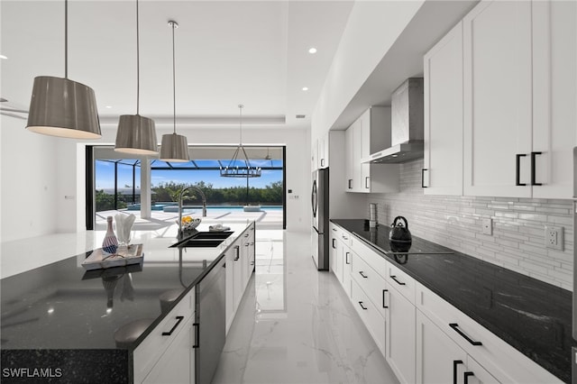 kitchen featuring pendant lighting, sink, stainless steel appliances, a center island with sink, and wall chimney range hood