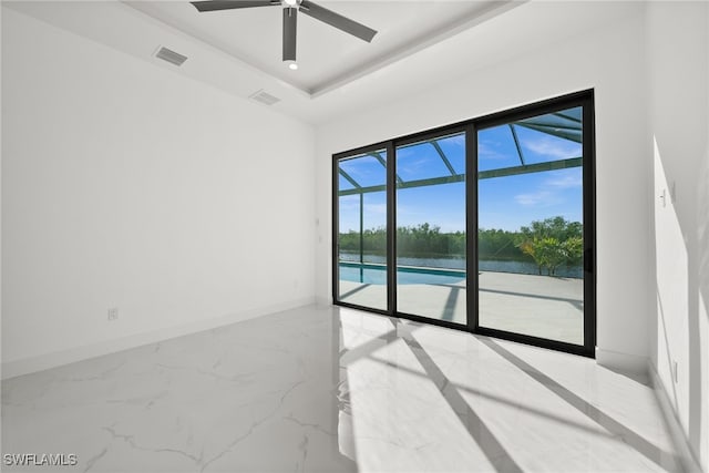 spare room with a water view, ceiling fan, and a tray ceiling