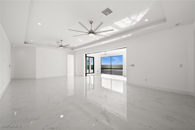 empty room featuring a raised ceiling and ceiling fan