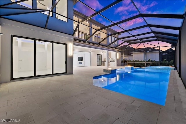 pool at dusk featuring a lanai and a patio