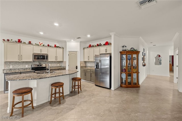 kitchen featuring sink, a kitchen breakfast bar, stainless steel appliances, an island with sink, and dark stone counters