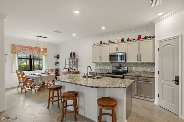 kitchen with sink, tasteful backsplash, hanging light fixtures, an island with sink, and stainless steel appliances