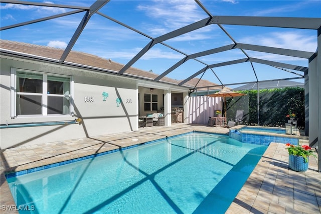 view of pool featuring an in ground hot tub, glass enclosure, and a patio area