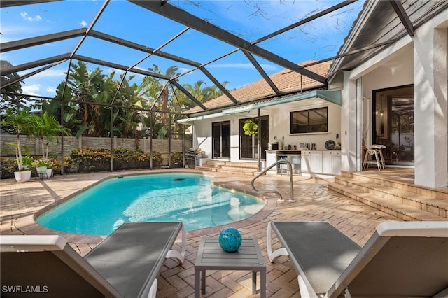 view of pool with a lanai, a patio, and exterior kitchen