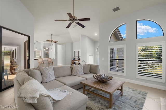 tiled living room with ceiling fan and high vaulted ceiling