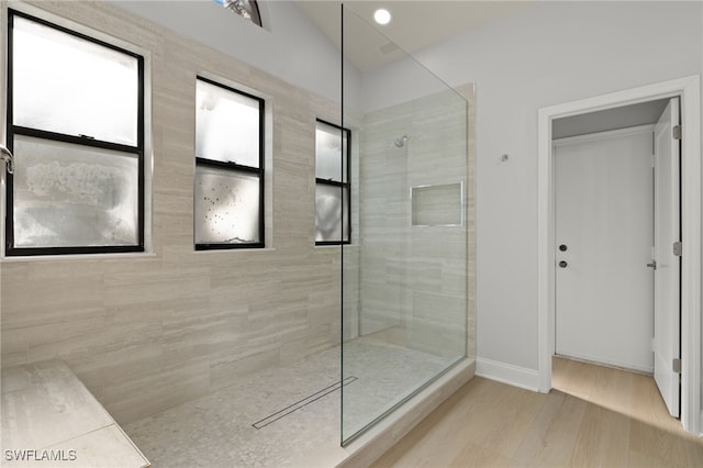 bathroom featuring a tile shower and vaulted ceiling