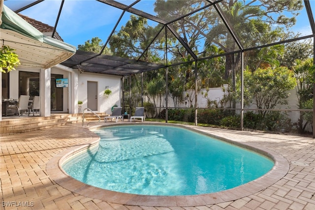 view of pool with glass enclosure and a patio area