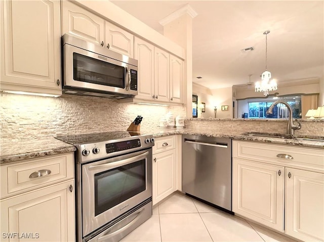 kitchen with sink, backsplash, light tile patterned floors, light stone counters, and stainless steel appliances