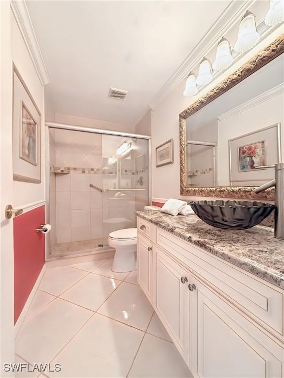 bathroom featuring vanity, ornamental molding, a shower with shower door, tile patterned floors, and toilet