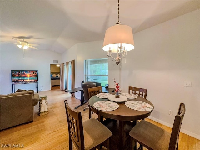 dining area featuring ceiling fan with notable chandelier, vaulted ceiling, and light wood-type flooring