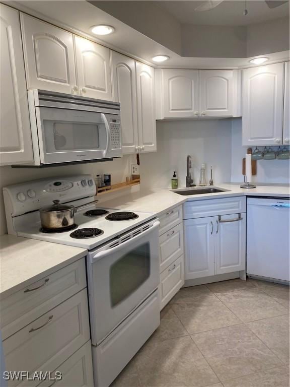 kitchen with sink, white appliances, white cabinets, and light tile patterned flooring