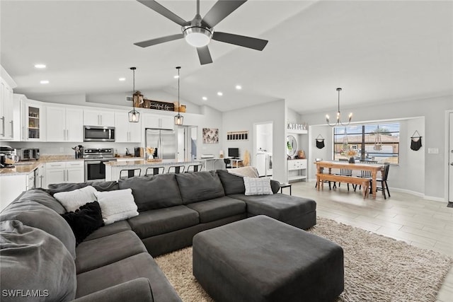 living room with ceiling fan with notable chandelier and vaulted ceiling