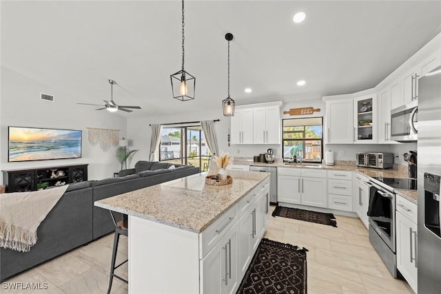 kitchen with white cabinetry, pendant lighting, a center island, and appliances with stainless steel finishes