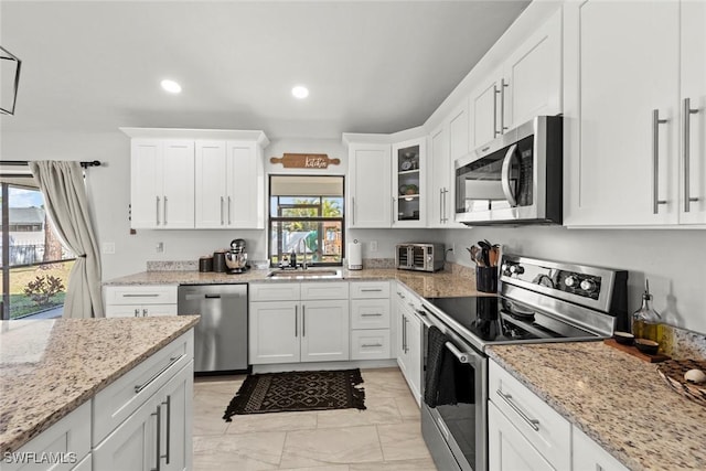 kitchen featuring white cabinetry, stainless steel appliances, light stone countertops, and sink