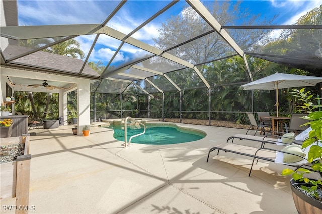 view of pool featuring ceiling fan, glass enclosure, and a patio area