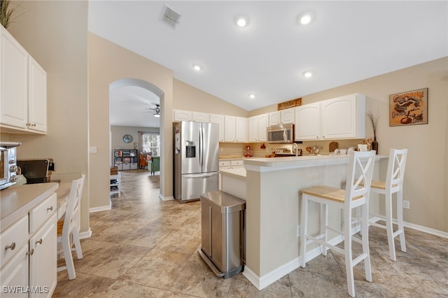 kitchen featuring vaulted ceiling, a breakfast bar, white cabinets, and appliances with stainless steel finishes