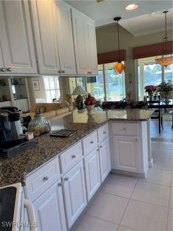 kitchen featuring dark stone countertops, kitchen peninsula, white cabinets, and decorative light fixtures