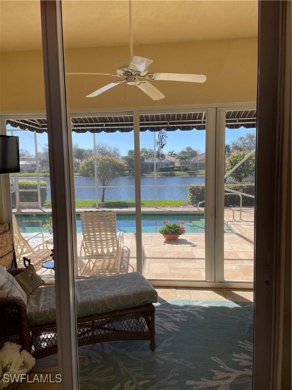 sunroom / solarium with ceiling fan and a water view