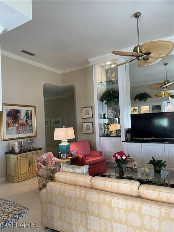 living room featuring light tile patterned floors, crown molding, built in shelves, and ceiling fan