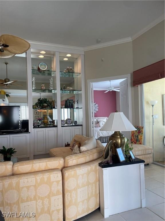 tiled living room featuring built in shelves, ceiling fan, and ornamental molding