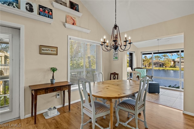 dining space with a water view, a notable chandelier, baseboards, and wood finished floors