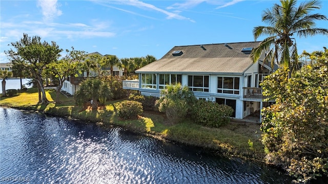 back of property with a sunroom and a water view