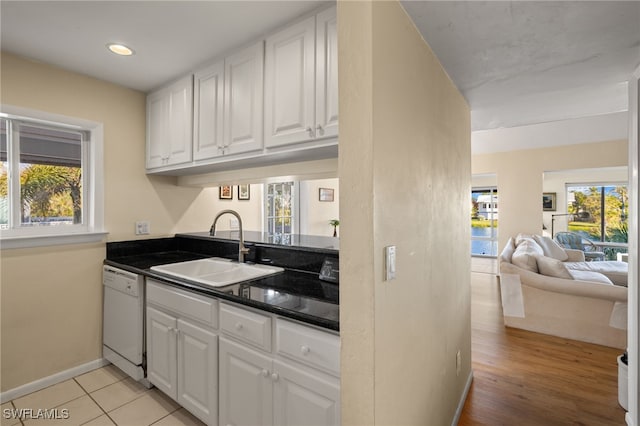 kitchen with dishwasher, dark countertops, a sink, and white cabinets