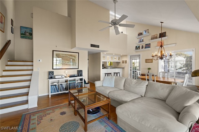 living area with visible vents, stairway, vaulted ceiling, wood finished floors, and baseboards