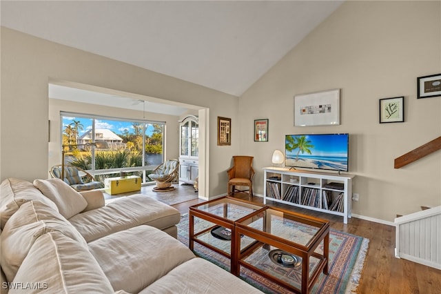 living area featuring high vaulted ceiling, wood finished floors, and baseboards