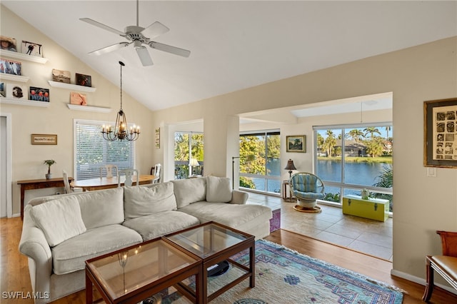 living room featuring ceiling fan with notable chandelier, high vaulted ceiling, wood finished floors, and baseboards