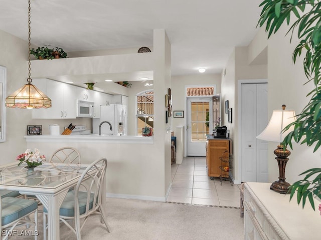 kitchen featuring light tile patterned floors, kitchen peninsula, pendant lighting, white appliances, and white cabinets