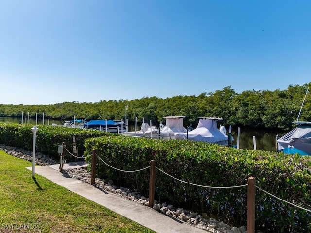 view of property's community featuring a water view, a lawn, and a boat dock