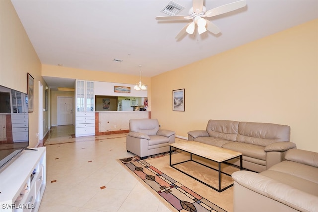 tiled living room with ceiling fan with notable chandelier