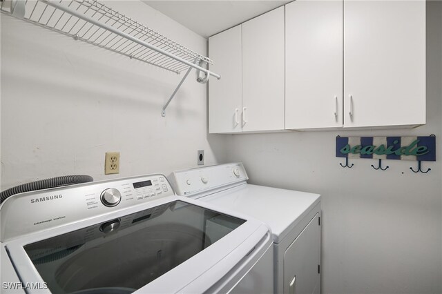 washroom with cabinets and washing machine and dryer