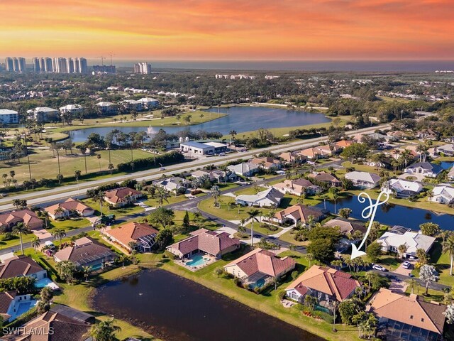 aerial view at dusk featuring a water view