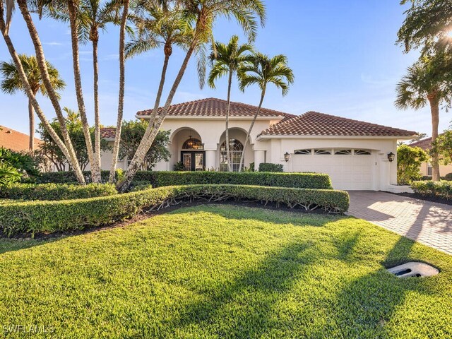 28880 Trenton Ct, Bonita Springs, FL 34134 - mediterranean / spanish-style house featuring an attached garage, stucco siding, decorative driveway, a front lawn, and a tiled roof