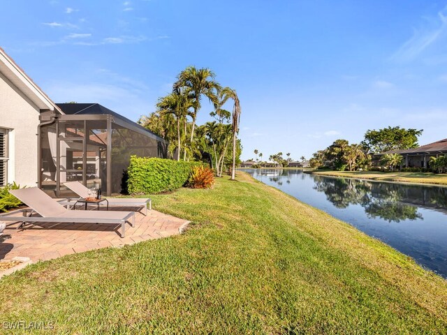 view of yard with a patio, a water view, and a lanai